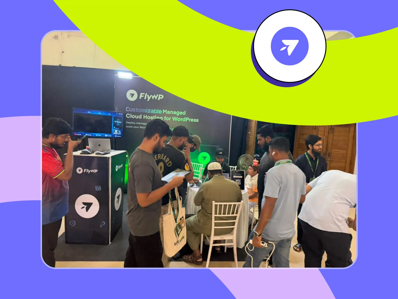 Visitors lining up and gathering at the FlyWP booth beside the booth banner and counter